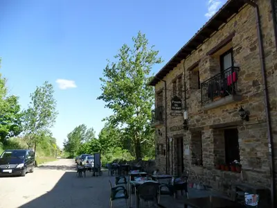 a building with tables and chairs next to a street at Posada El Tesin in Rabanal del Camino