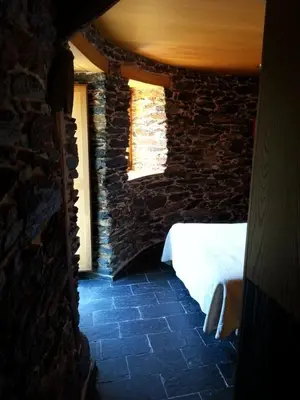 a bedroom with a bed and a stone wall at Palloza Baltasar in Castelo