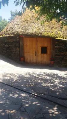 a building with a thatch roof with two doors at Palloza Baltasar in Castelo