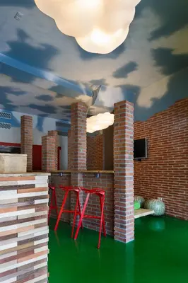 a room with two red chairs and a brick wall at Blanco Albergue in Santiago de Compostela