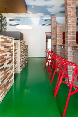 a room with a green floor and red chairs at Blanco Albergue in Santiago de Compostela