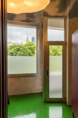 a room with two windows and a green floor at Blanco Albergue in Santiago de Compostela