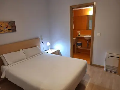 a bedroom with a white bed and a bathroom at Blanco Albergue in Santiago de Compostela