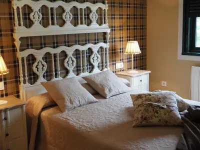 a bedroom with a large white bed with two lamps at La Calleja in Arzúa
