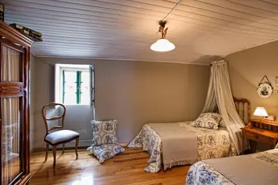 a bedroom with two beds and a chair and a window at La Calleja in Arzúa