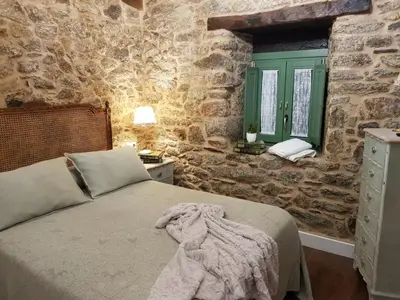 a bedroom with a bed and a stone wall at La Calleja in Arzúa