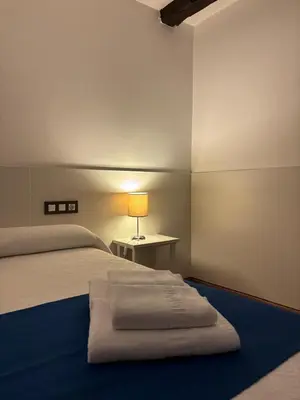 a bedroom with a bed and a table with a lamp at Pension Via-Stella in Santiago de Compostela