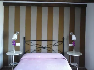 a bedroom with a bed and two tables with purple flowers at Hostal Restaurante Parajes in Castropol