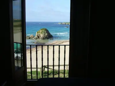 a view of a beach from a room with a window at Hostal Restaurante Parajes in Castropol