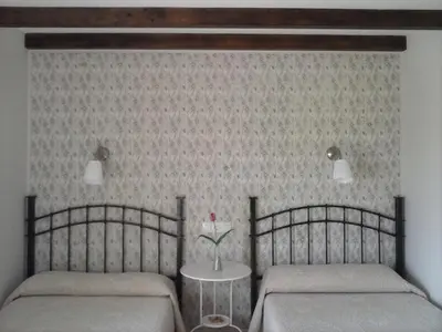 a bedroom with two beds and a table with a vase at Hostal Restaurante Parajes in Castropol