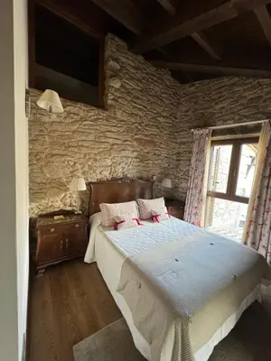 a bedroom with a large bed with a stone wall at A Eira da Laxe in Cerdedo