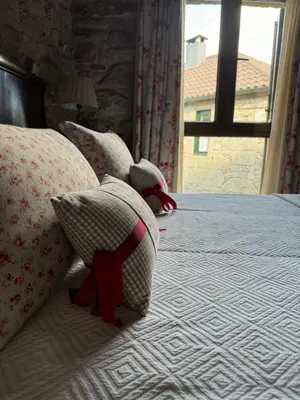 a bed with four pillows on it with a window at A Eira da Laxe in Cerdedo