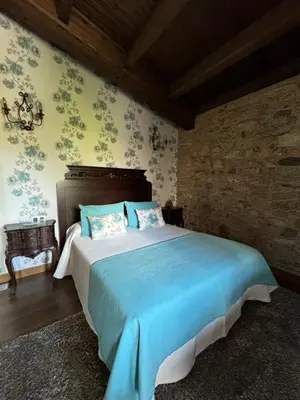 a bedroom with a large bed with blue sheets at A Eira da Laxe in Cerdedo