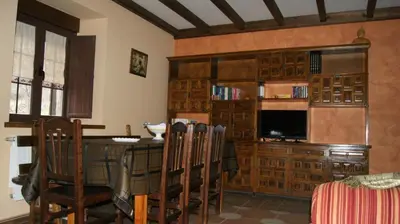 a living room with a table and chairs and a television at Casa rural el Molino del Botero in Coso