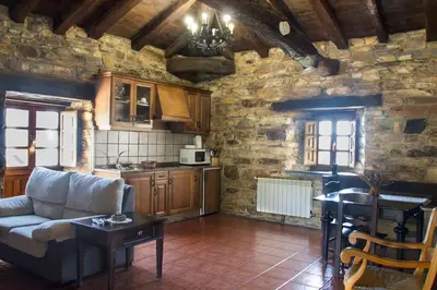 a living room with a couch and a kitchen at Apartamentos rurales Vilarchao in Vilarchao