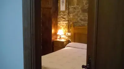 a bedroom with a bed and a lamp on a table at Apartamentos rurales Vilarchao in Vilarchao