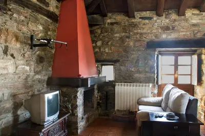 a living room with a tv and a stone wall at Apartamentos rurales Vilarchao in Vilarchao
