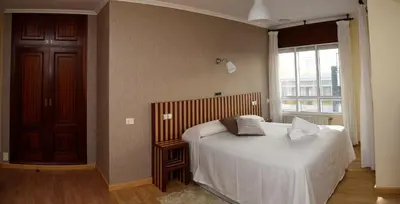 a bedroom with a bed with white sheets and a window at Hotel Villa De Ribadeo in Ribadeo
