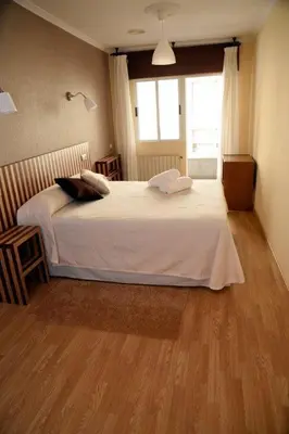 a bedroom with a large white bed with a window at Hotel Villa De Ribadeo in Ribadeo