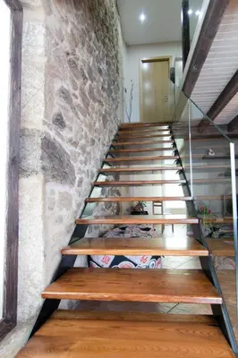 a staircase with wooden steps and a stone wall at Casa Carla in Palas de Rei