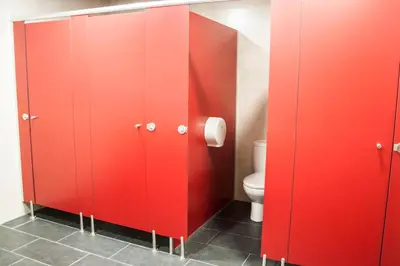 a bathroom with red stalls with a toilet in it at De Camino in Arzúa