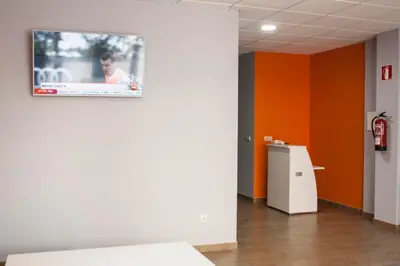 a television on a wall in a room with orange walls at De Camino in Arzúa