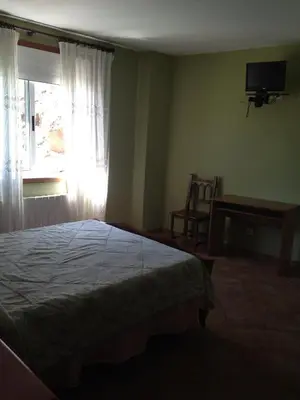 a bedroom with a bed and a window and a chair at Pension Meson Paz in Puentedeume