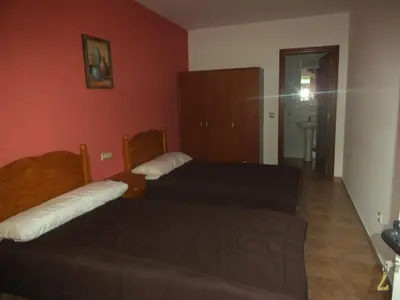 two beds in a room with red walls at Pension Meson Paz in Puentedeume