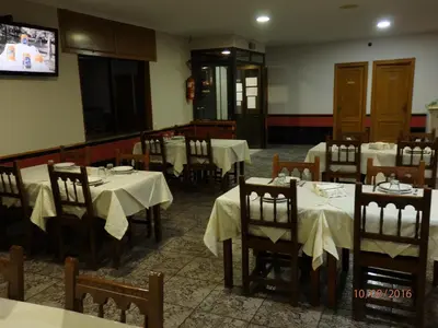 a dining room with tables and chairs and a tv at Pension Meson Paz in Puentedeume