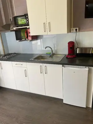 a kitchen with white cabinets and a sink at A Fontana de Luxo Apartamentos in Portomarin