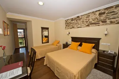 a hotel room with two beds and a tv at La Casona de Lazúrtegui in Ribadeo