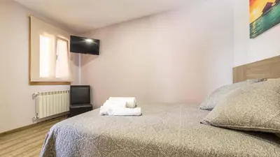 a bedroom with a bed with a television on the wall at Pensión Pereiro in Melide