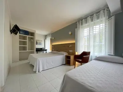 a hotel room with two beds and a chair at Hotel Amadora - Admite mascotas in Barreiros