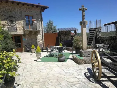 a stone patio with tables and a cross in front of a building at Alcázar Milmanda in Milmanda