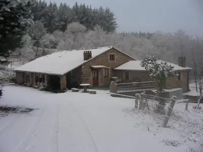 a house covered in snow with a road in front of it at O Muiño de Pena in O Pino
