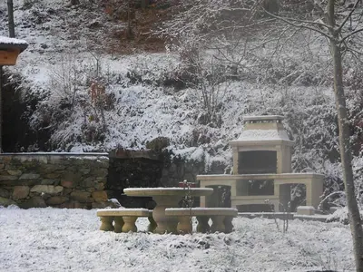 a snow covered garden with a bench and a light at O Muiño de Pena in O Pino