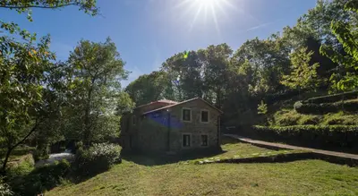 an old house on a hill with the sun in the sky at O Muiño de Pena in O Pino