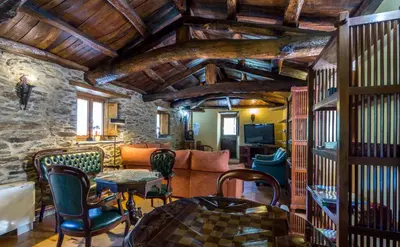 a living room with wooden ceilings and a stone wall at O Muiño de Pena in O Pino