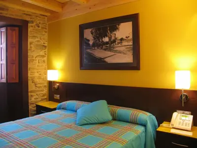 a hotel room with a bed and a telephone at Hotel Rolle in Ribadeo