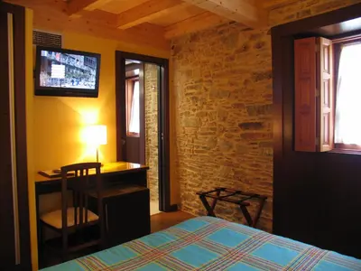 a bedroom with a bed and a desk and a television at Hotel Rolle in Ribadeo