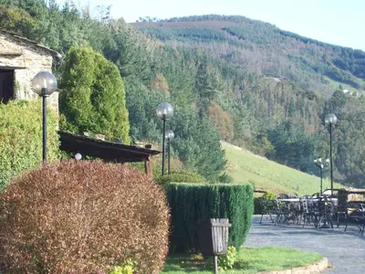 a garden with tables and chairs and a mountain at La Rectoral in Taramundi