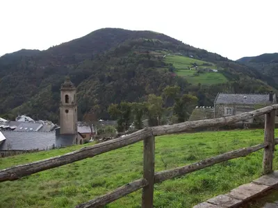 a wooden fence in a field with a mountain at La Rectoral in Taramundi