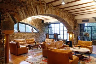 a living room with leather furniture and a stone wall at La Rectoral in Taramundi
