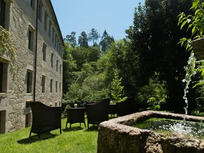 a garden with chairs and a fountain next to a building at A Quinta Da Auga Hotel Spa Relais & Chateaux in Santiago de Compostela