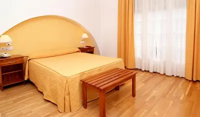 a bedroom with a bed and a bench and a window at Hotel Valcarce Camino de Santiago in La Portela de Valcarce