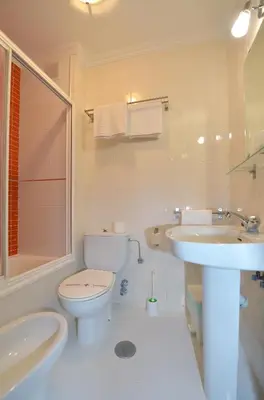 a white bathroom with a toilet and a sink at Santa Cruz in Ribadeo