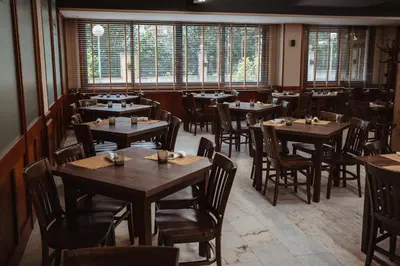 a restaurant with wooden tables and chairs and windows at Hotel Scala in Padrón