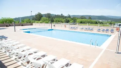 a swimming pool with white chairs and a bunch ofitures at Hotel Scala in Padrón