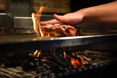 a person holding a piece of meat over a fire at Hotel Scala in Padrón