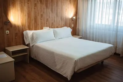 a bedroom with a large bed with white sheets and a window at Hotel Scala in Padrón